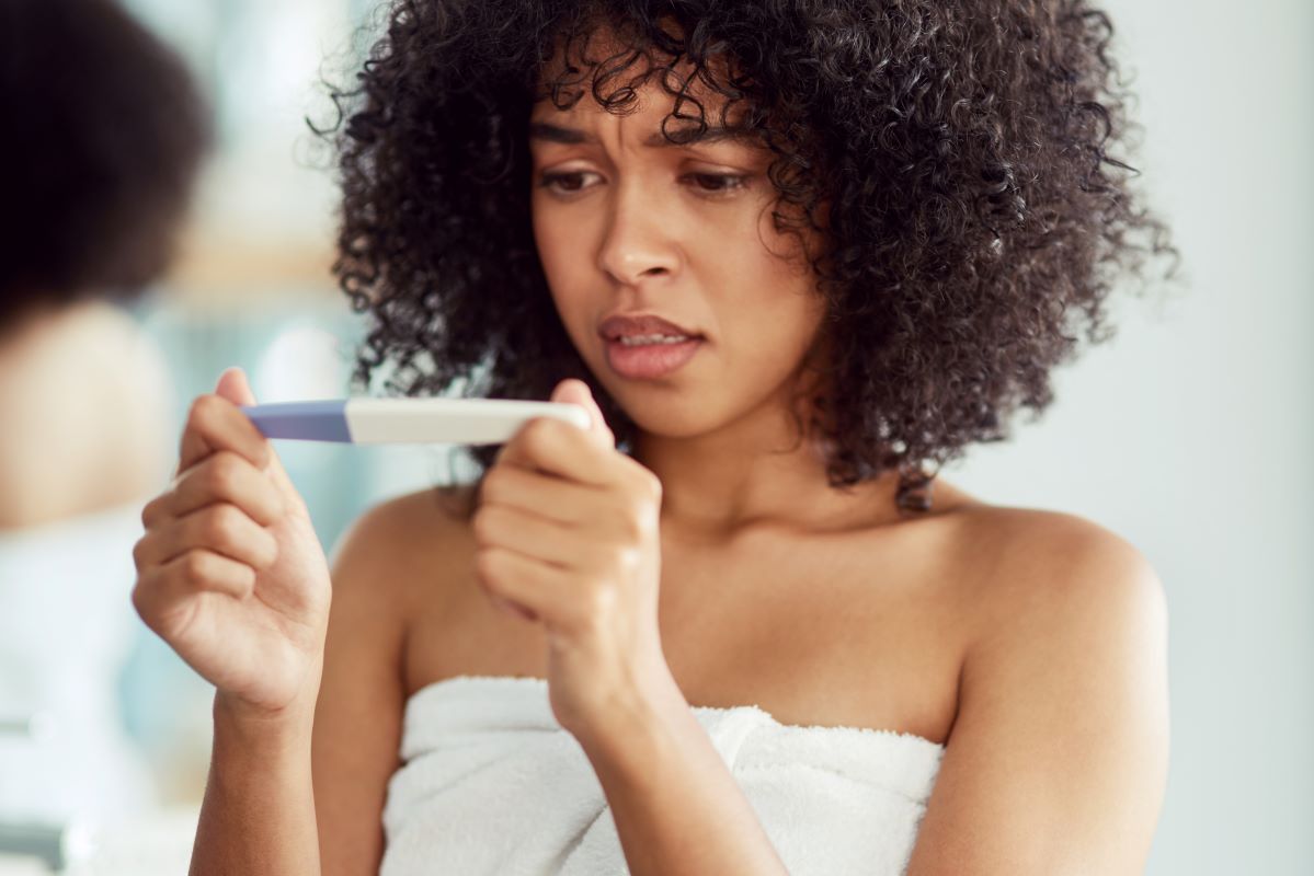 Woman looks at pregnancy test in bathroom Expect the unexpected